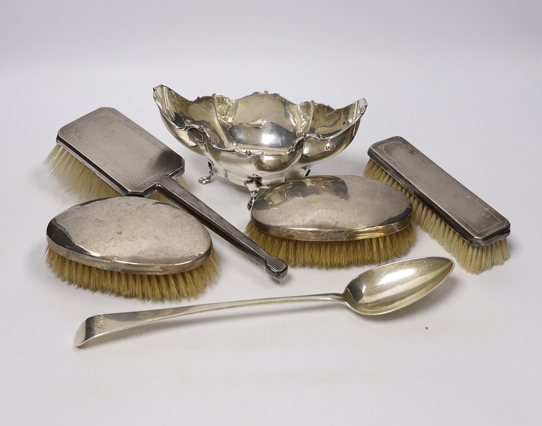 A George III silver Old English pattern basting spoon, with base marks, date letter rubbed, an Edwardian silver bowl and four silver mounted brushes.